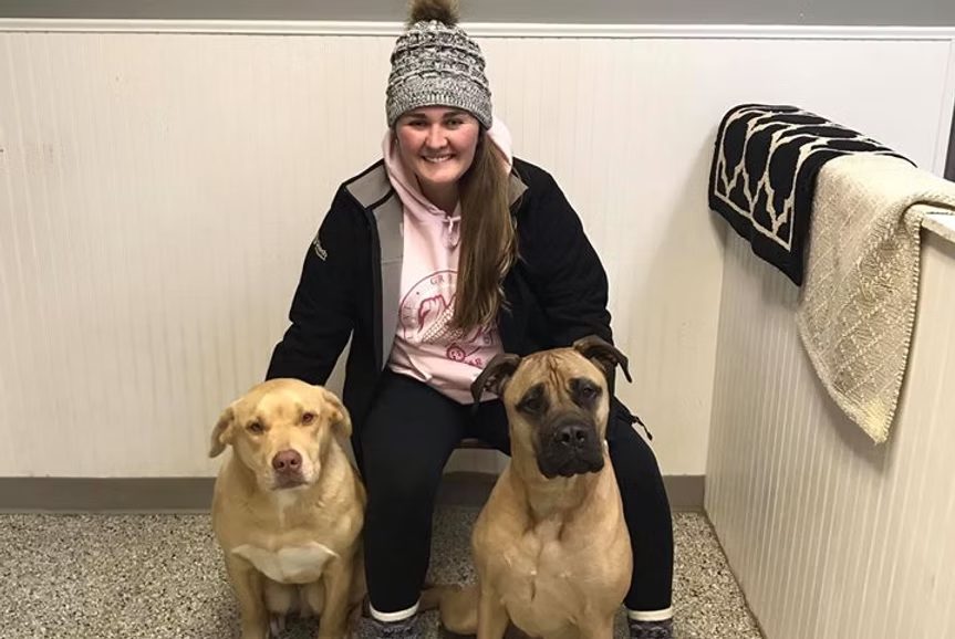 A Double K team member kneeling beside two friendly dogs